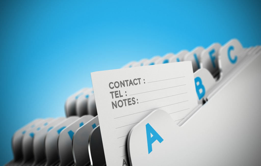 Folder tab organized alphabetically with focus on a contact note, blue background. Conceptual business image for illustration of customer file, client data management or address list.
